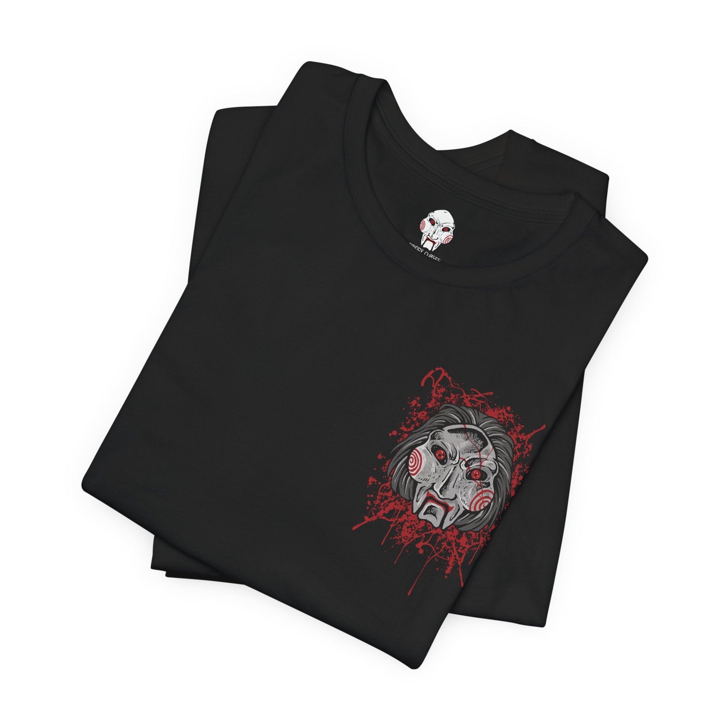Image 6 of a T-Shirt artwork depicting Billy the Puppet emerging from darkness with his tricycle positioned beneath a harsh spotlight. Shadows stretch across the floor while old television screens and mechanical traps fill the background. This design reflects the disturbing symbolism of Jigsaw’s messenger, embodying dread, manipulation, and the cruel tests that define the Saw franchise.